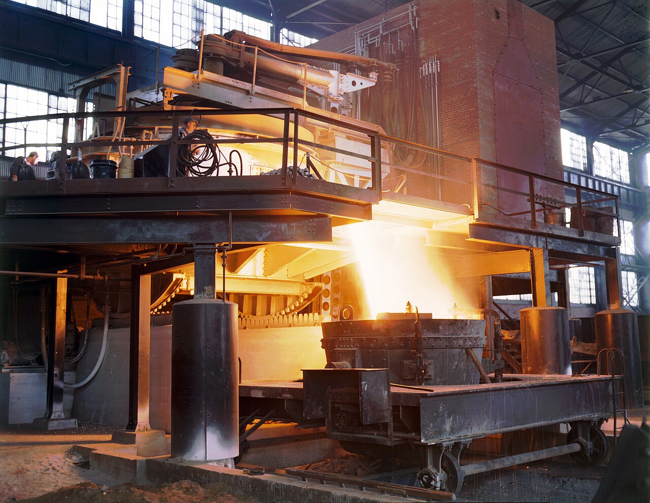 Historical electric steel furnace pouring molten steel in an industrial hall